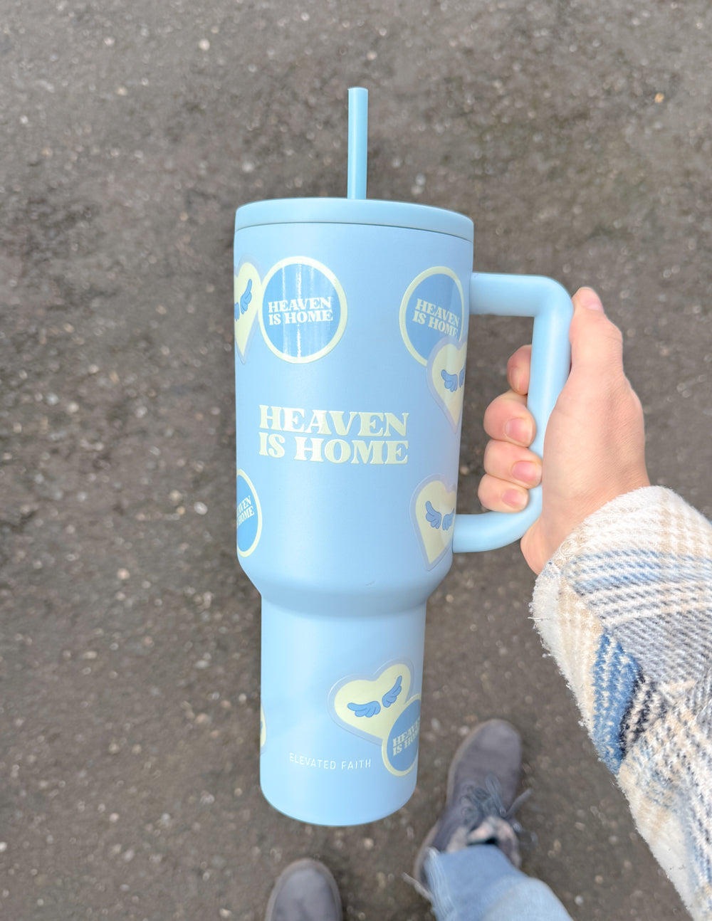 Light blue 40 oz tumbler with straw and handle, held in a hand outdoors