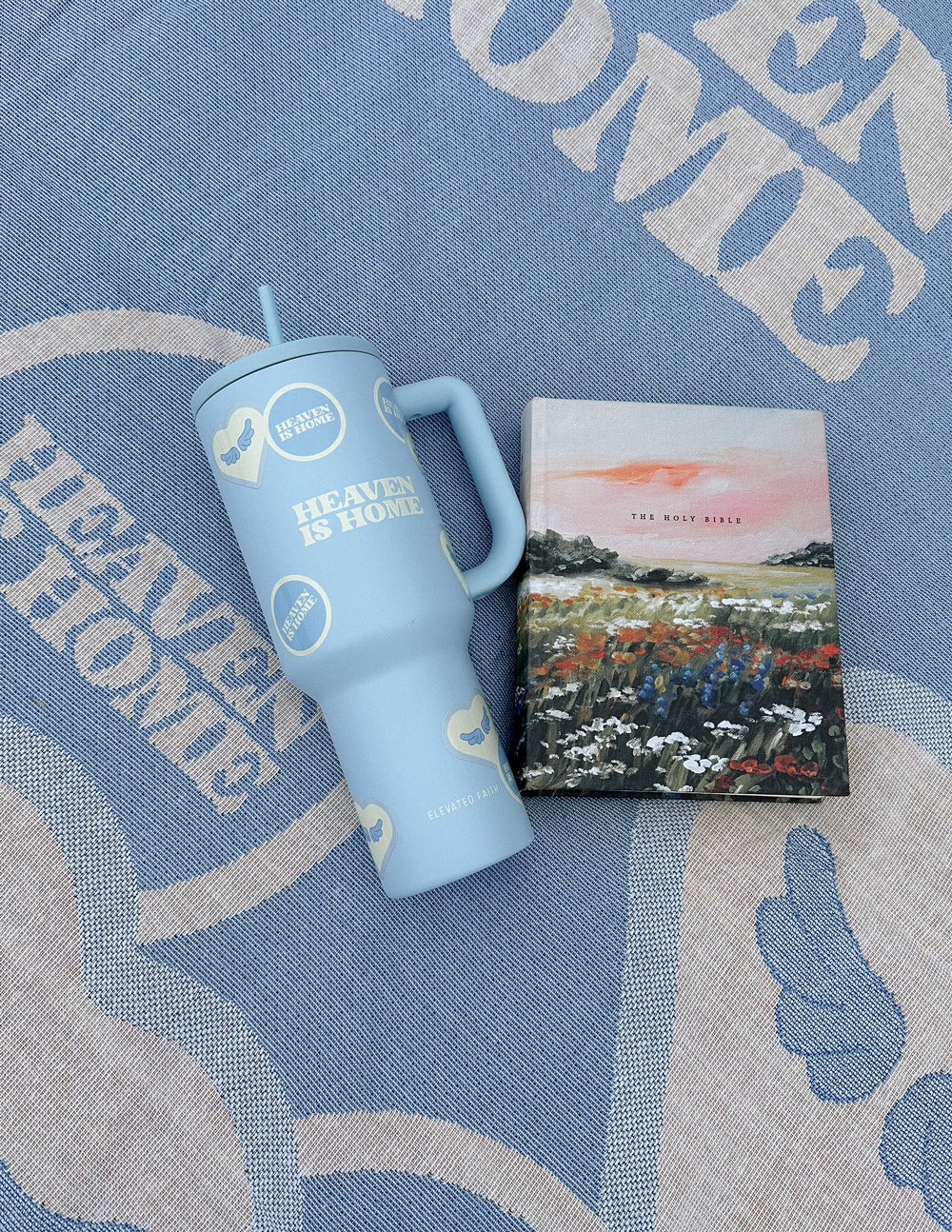 Light blue 40 oz tumbler with straw and handle resting on a blue fabric blanket