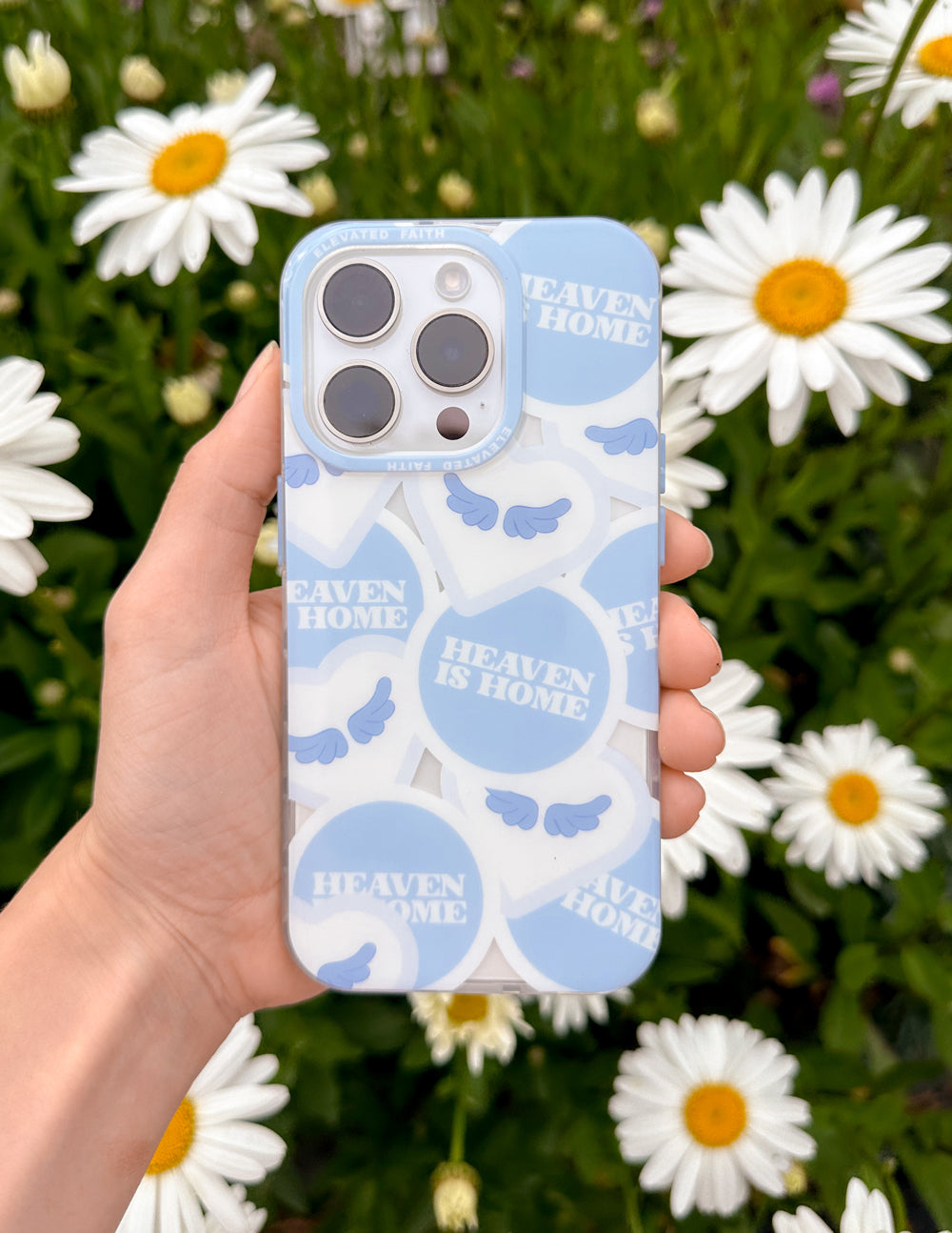 Light blue phone case held in hand, with Heaven Is Home text and cloud pattern