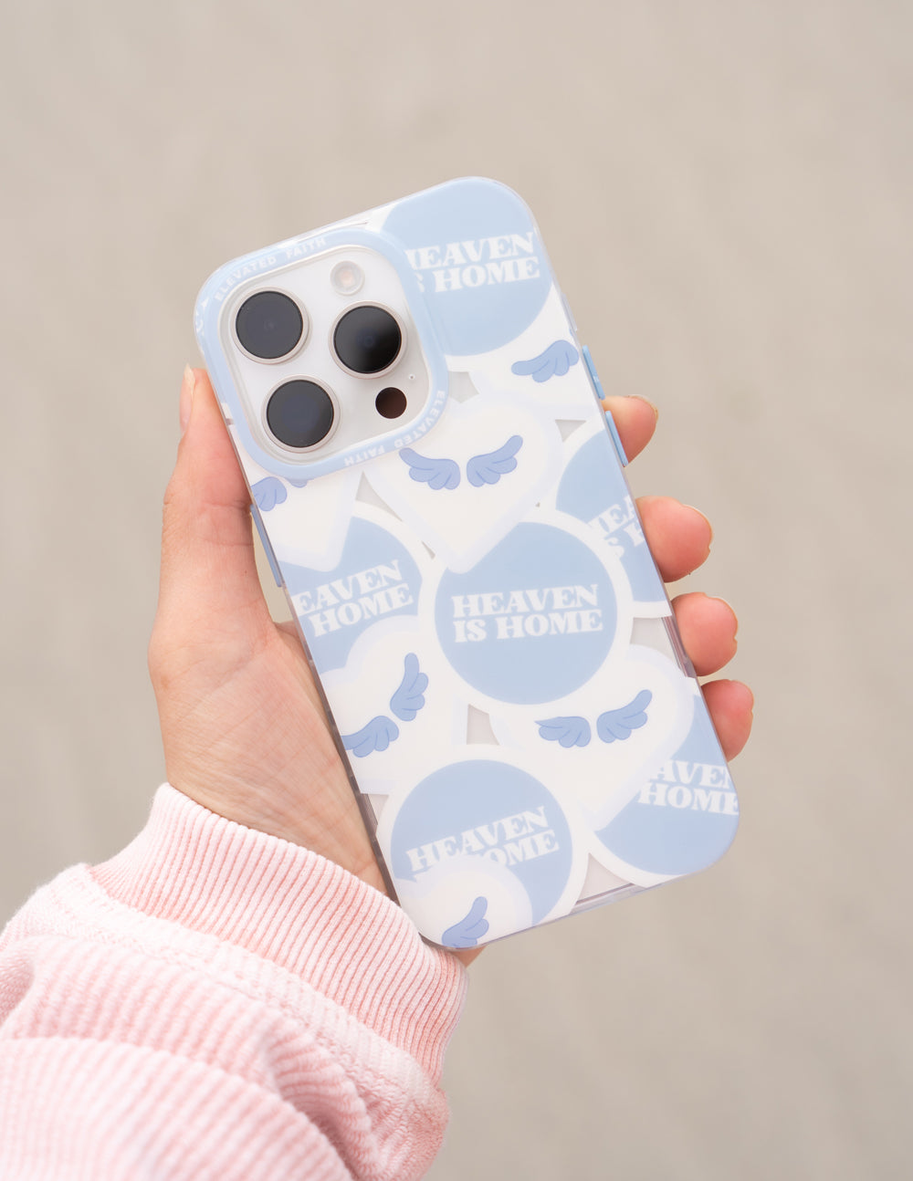 Light blue phone case in hand, featuring Heaven Is Home text and cloud print