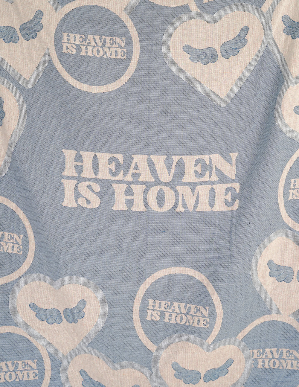 Light blue throw blanket close-up with 'HEAVEN IS HOME' text and hearts