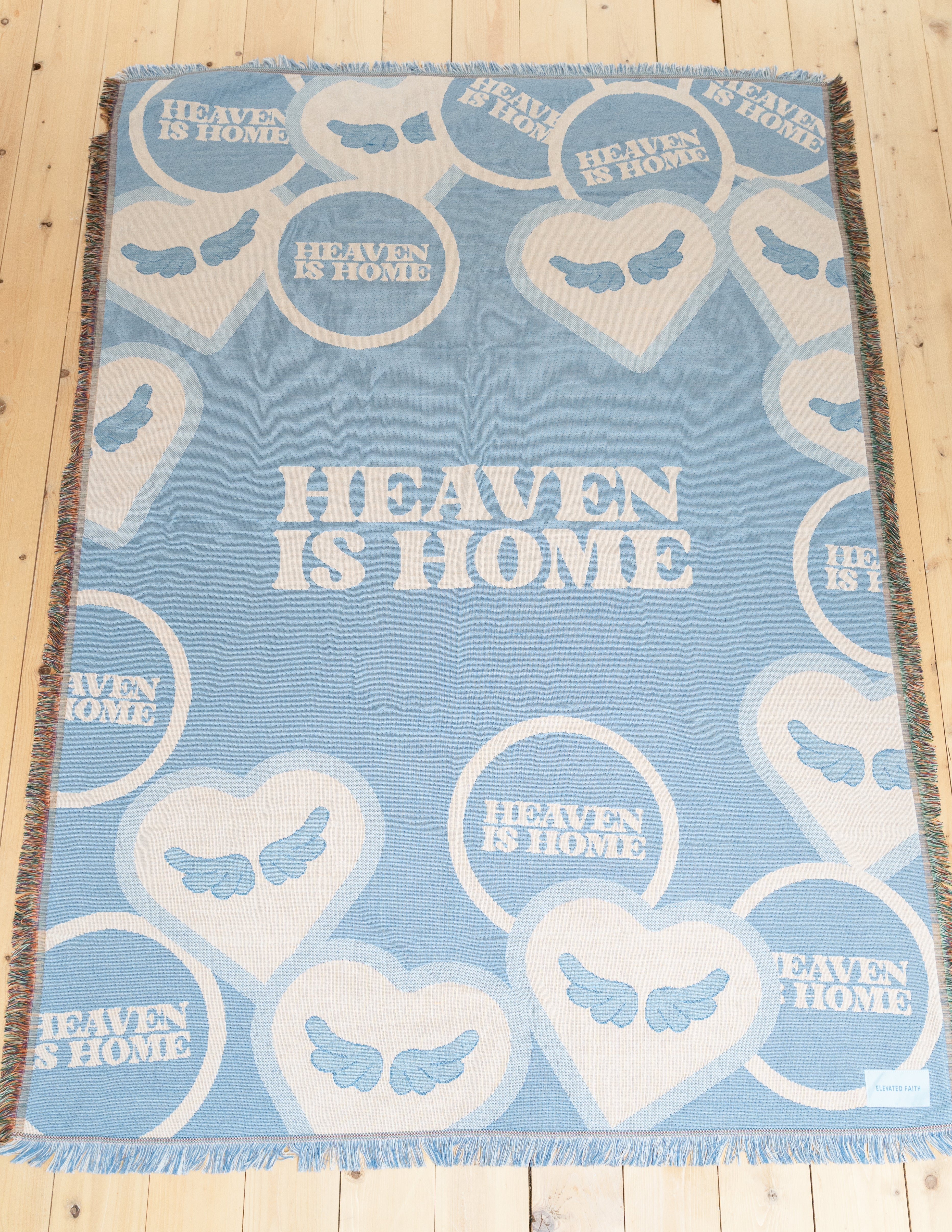Light blue heart-pattern throw blanket with 'Heaven is Home' text and fringed border