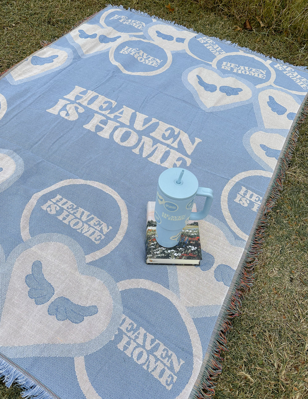 Light blue heart-pattern throw blanket with fringed edges on grass