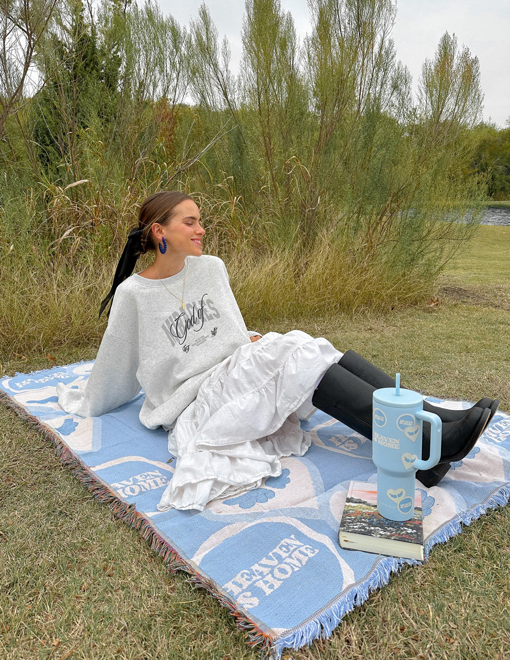 Light blue heart-pattern throw blanket with fringes, used outdoors