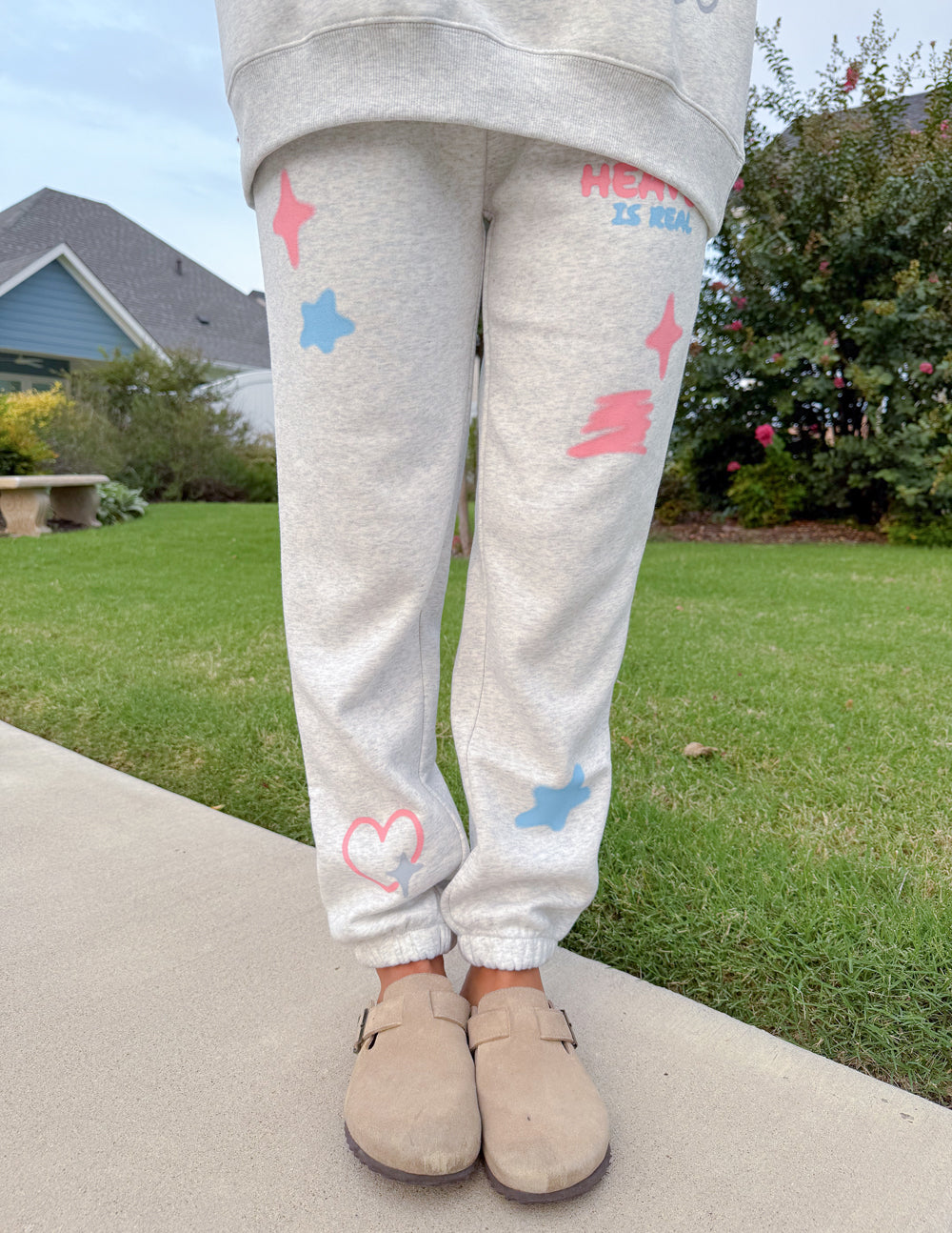 Light gray unisex sweatpants with pastel star and heart prints and elastic ankle cuffs