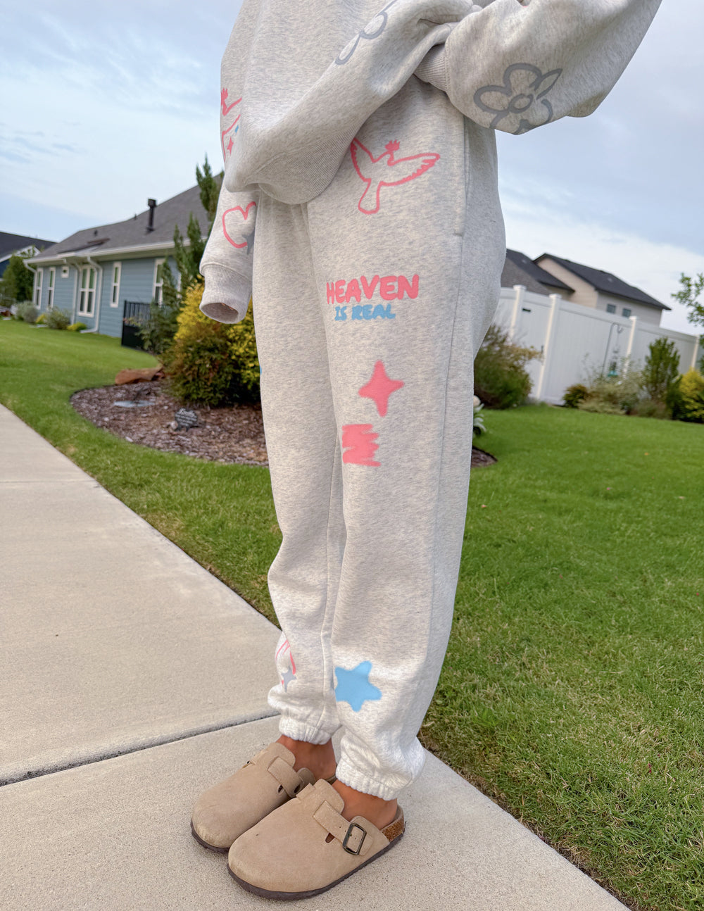 Light gray unisex sweatpants with pastel star and heart graphics and 'HEAVEN IS REAL' text