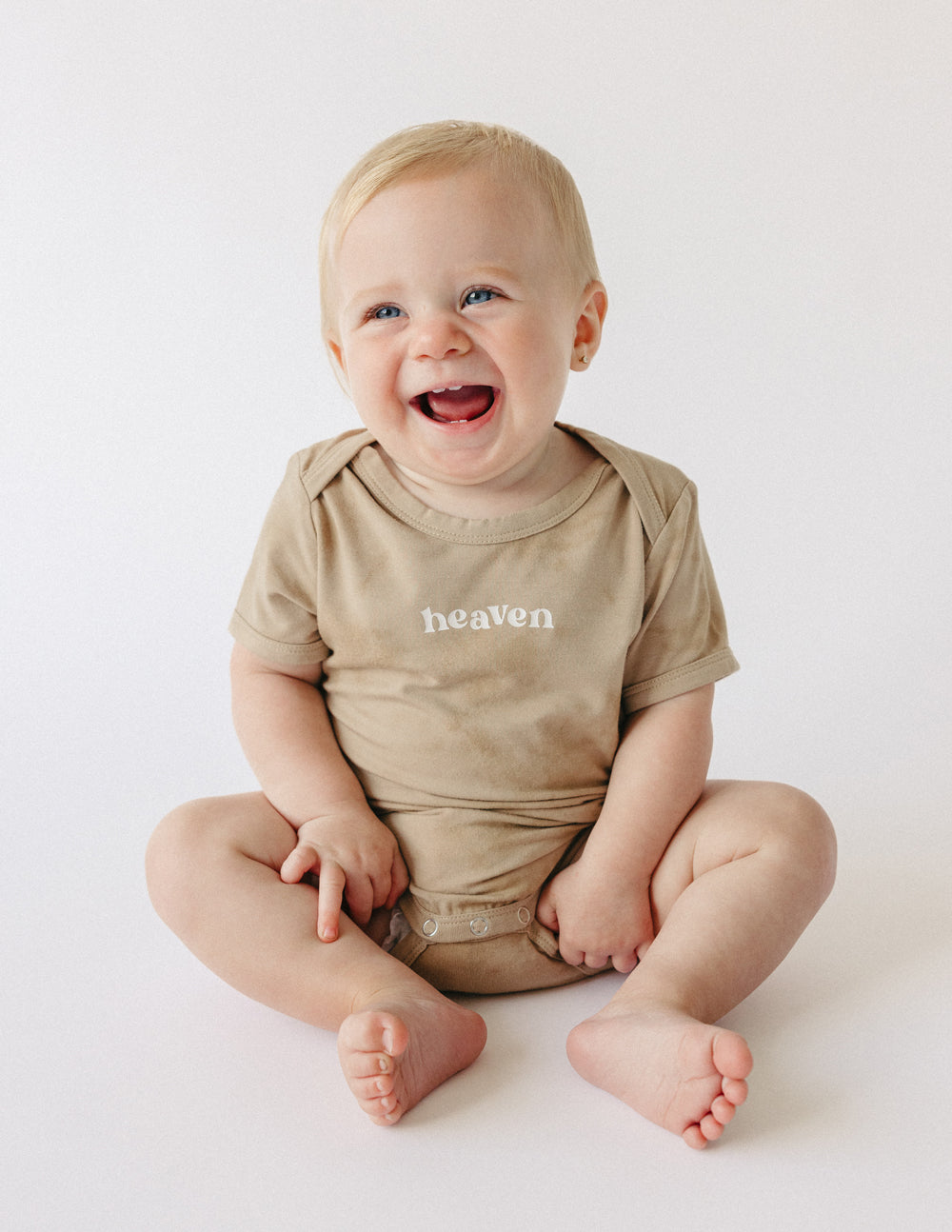 Tan baby onesie with 'heaven' chest print, short sleeves and round neckline