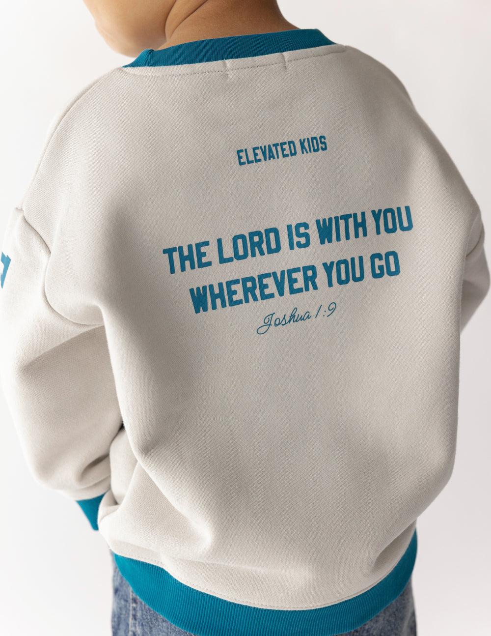 Kids crewneck sweatshirt back view in cream with teal “Elevated Kids” text