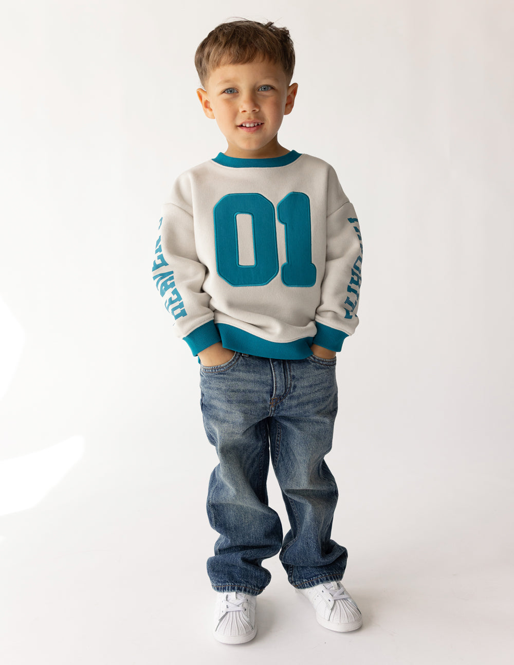 Kids crewneck sweatshirt in cream with teal 01 front graphic and ribbed teal collar
