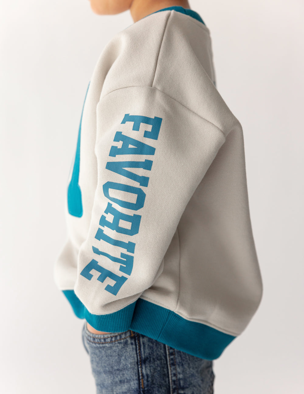 Kids crewneck sweatshirt, light gray with teal ribbed cuffs and sleeve text