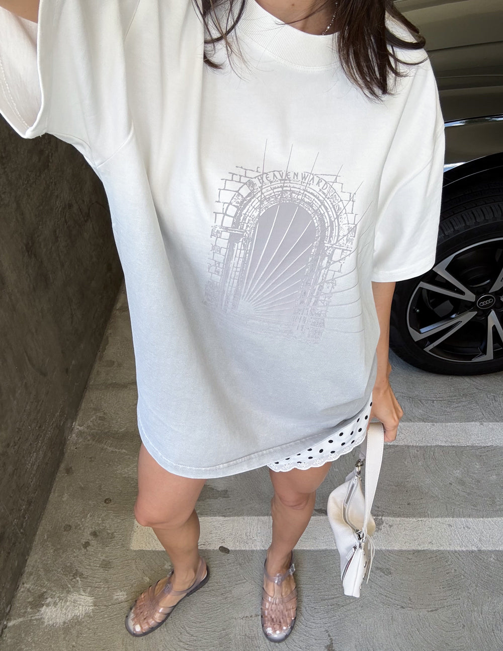 White heavyweight graphic tee with arched logo print, cropped view showing chest and hem.