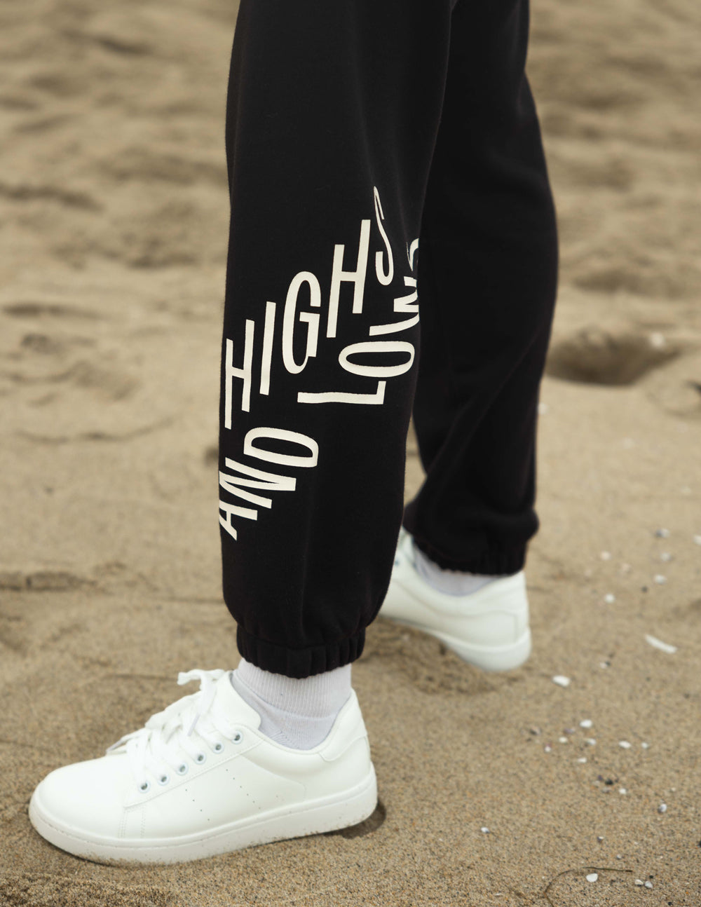 Unisex black sweatpants with large white logo print on left leg