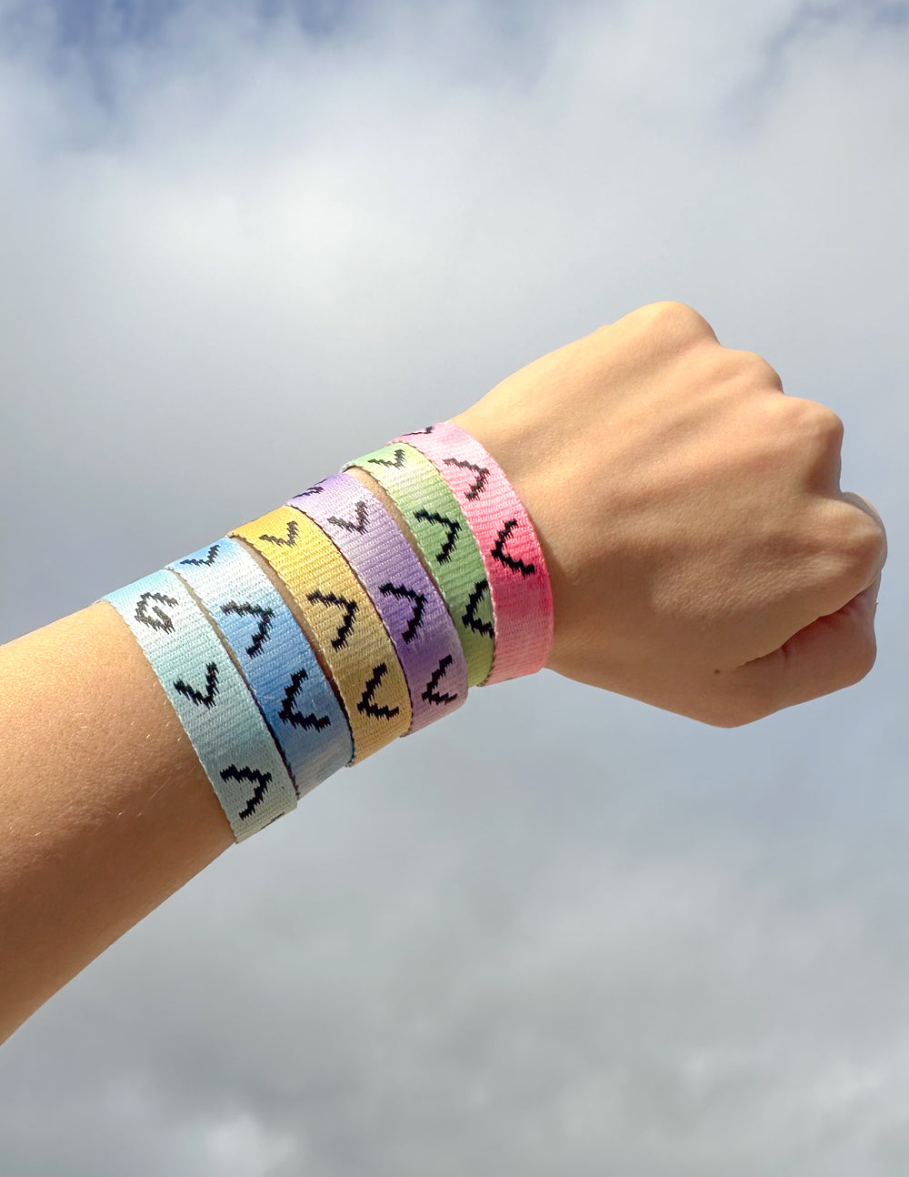 Tie-dye fabric bracelet set on wrist, pastel bands with repeating arrow-like icons