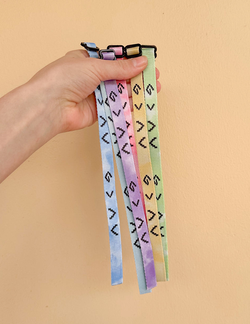 Adjustable tie-dye fabric bracelet bands with metal clasps, held in hand