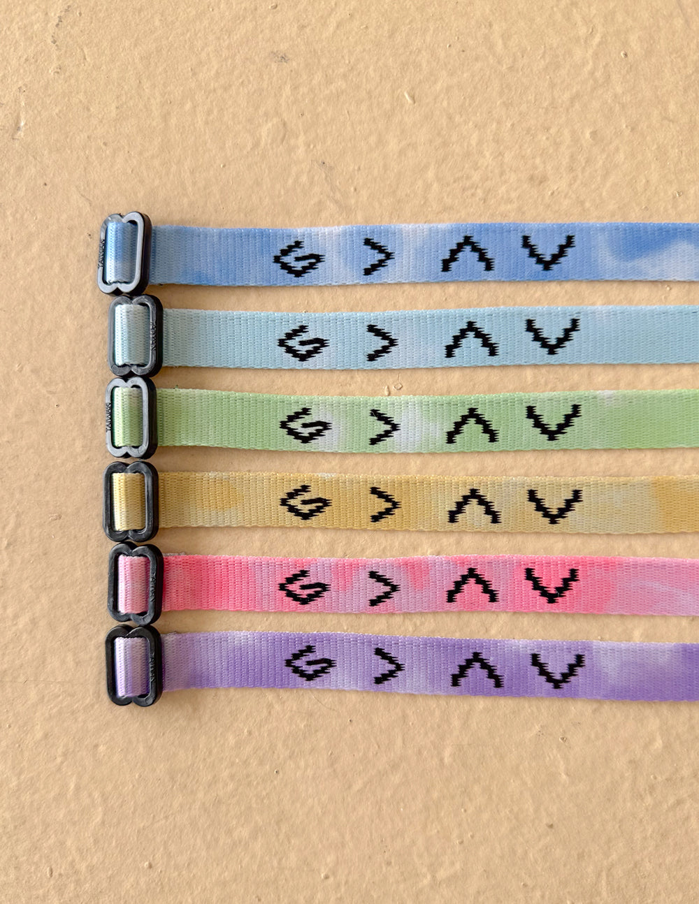 Set of five pastel tie-dye fabric bracelets with repeating arrow icons