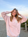 Unisex pink hoodie with front pocket and small chest heart-text graphic, hood up