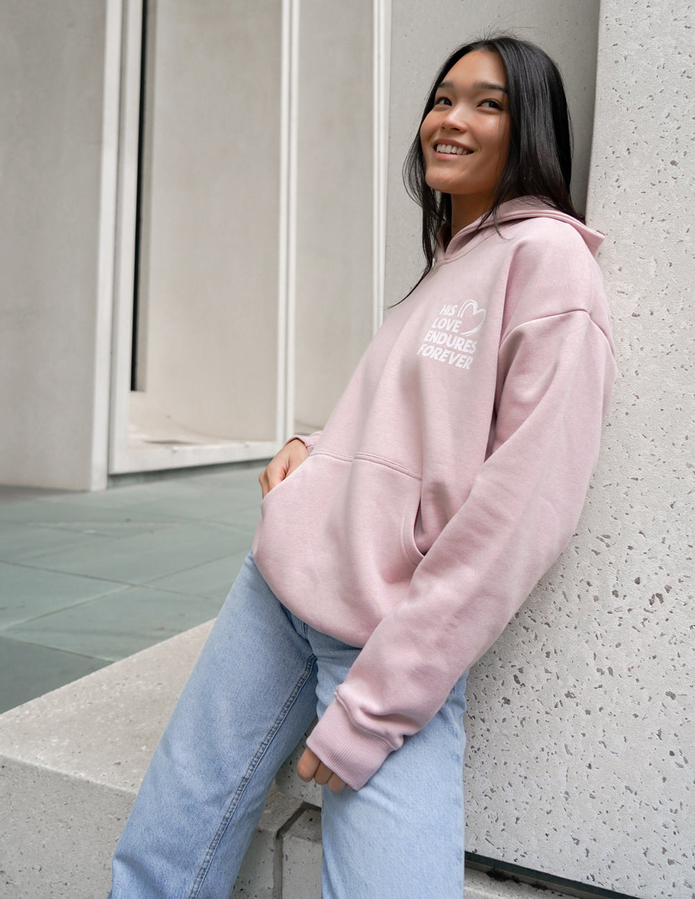 Unisex pink hoodie with chest logo, kangaroo pocket, and long sleeves