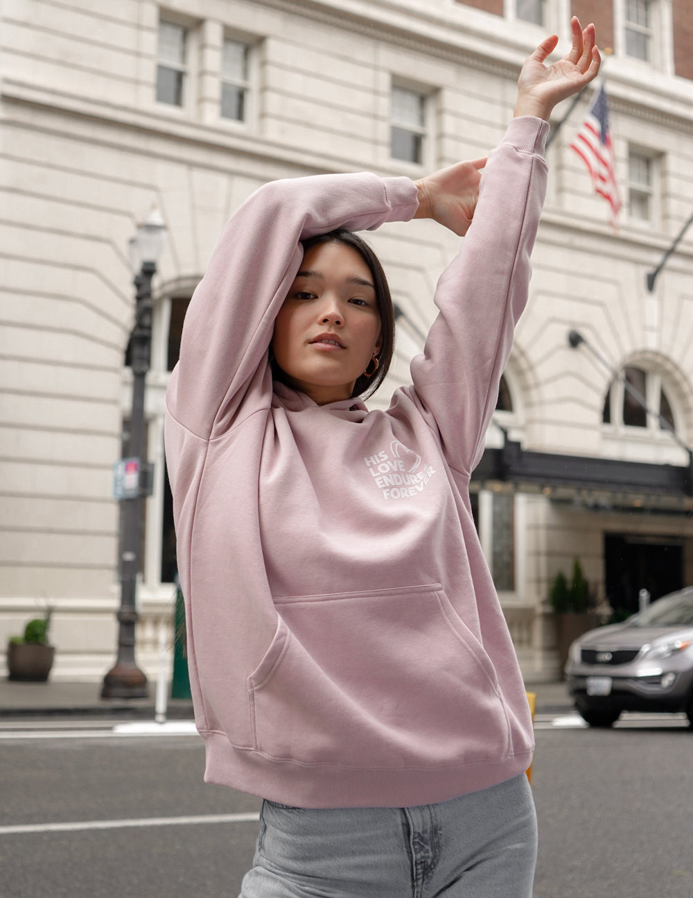 Unisex pink hoodie with hood up, kangaroo pocket, and small chest graphic