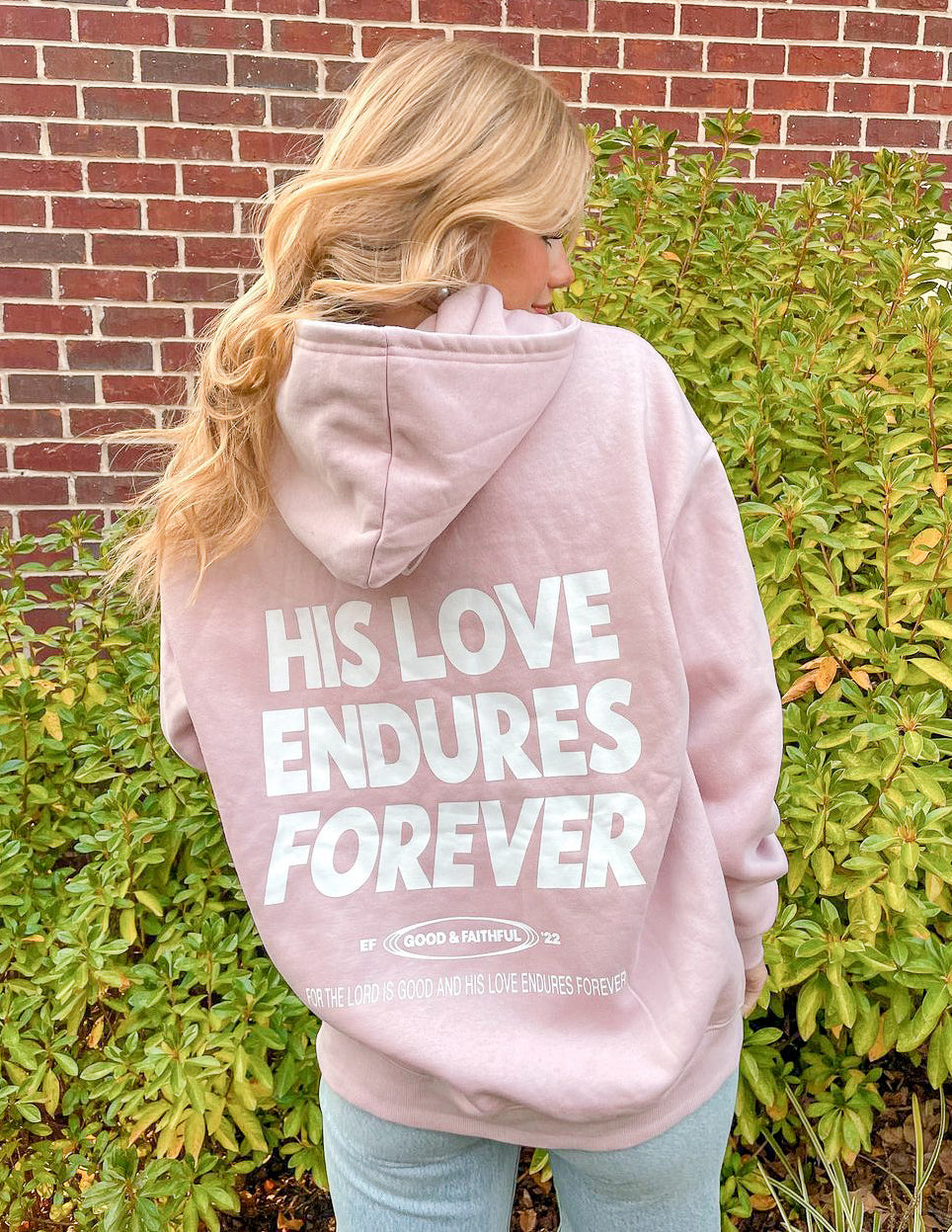Unisex pink hoodie back view with large heart and “HIS LOVE ENDURES FOREVER” text