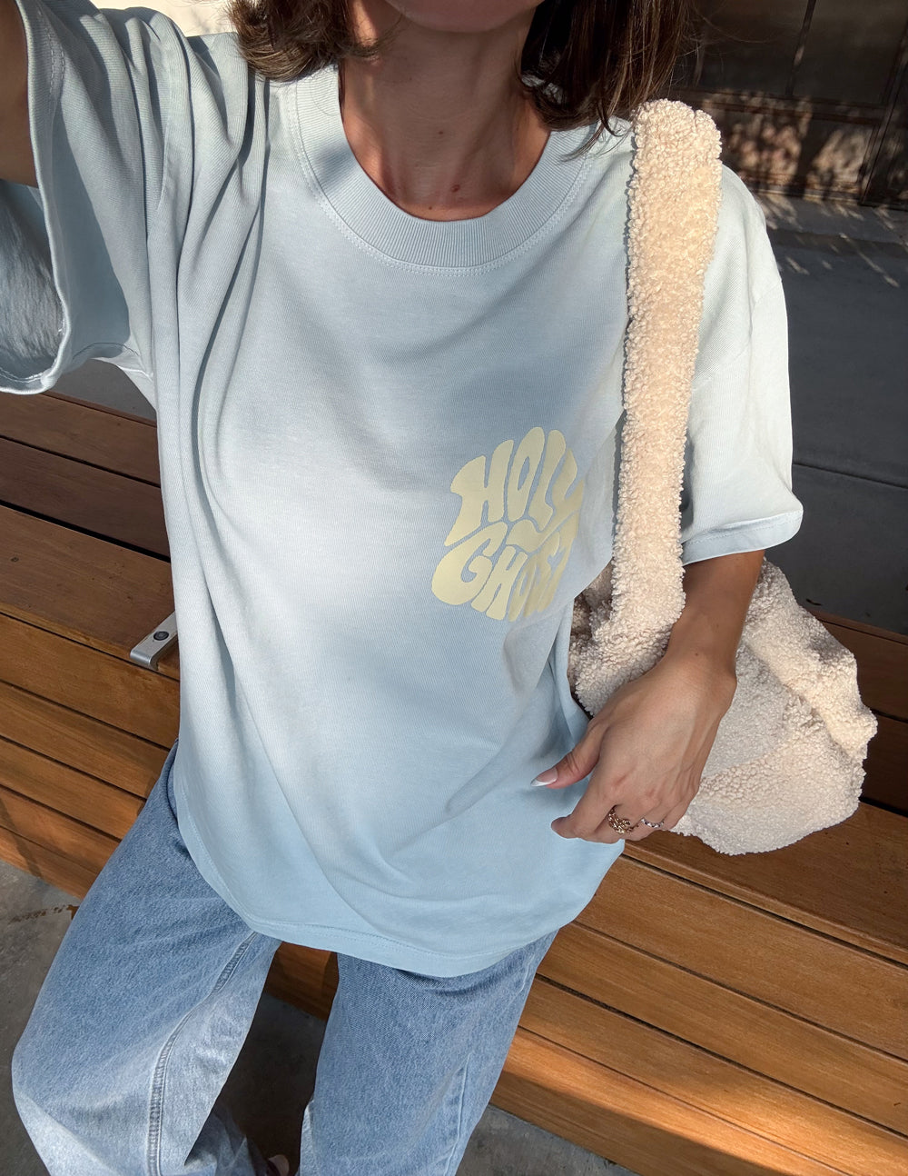 Light blue T-shirt close-up with front chest graphic logo and crew neck.