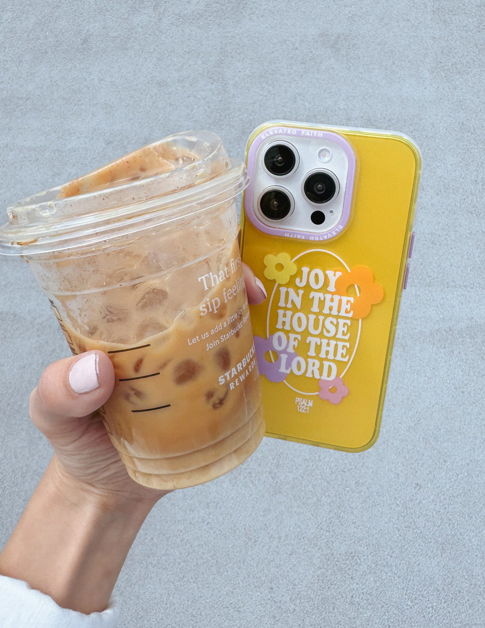 Yellow phone case with floral design and 'Joy in the House of the Lord' text, held