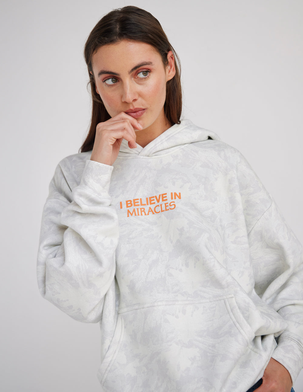 Light camo unisex hoodie with orange "I Believe in Miracles" front print and kangaroo pocket