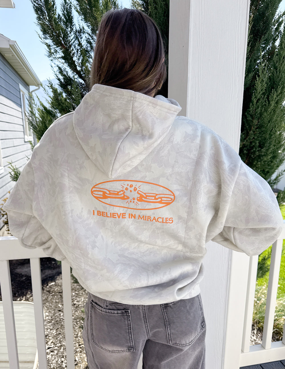 Light camo unisex hoodie back view with large orange "I Believe in Miracles" graphic