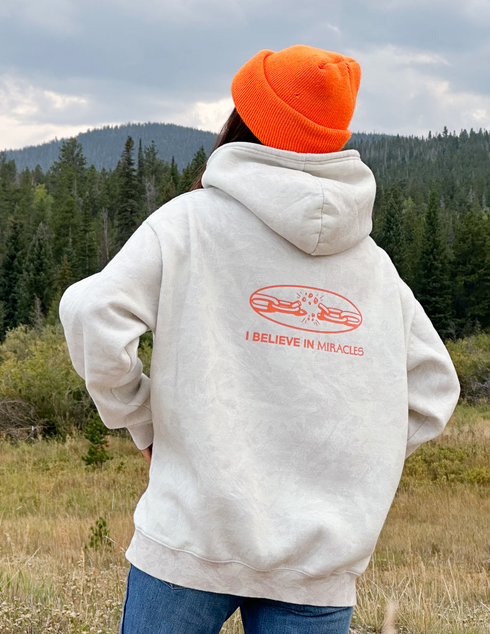 Light camo unisex hoodie with large orange back graphic "I Believe in Miracles"