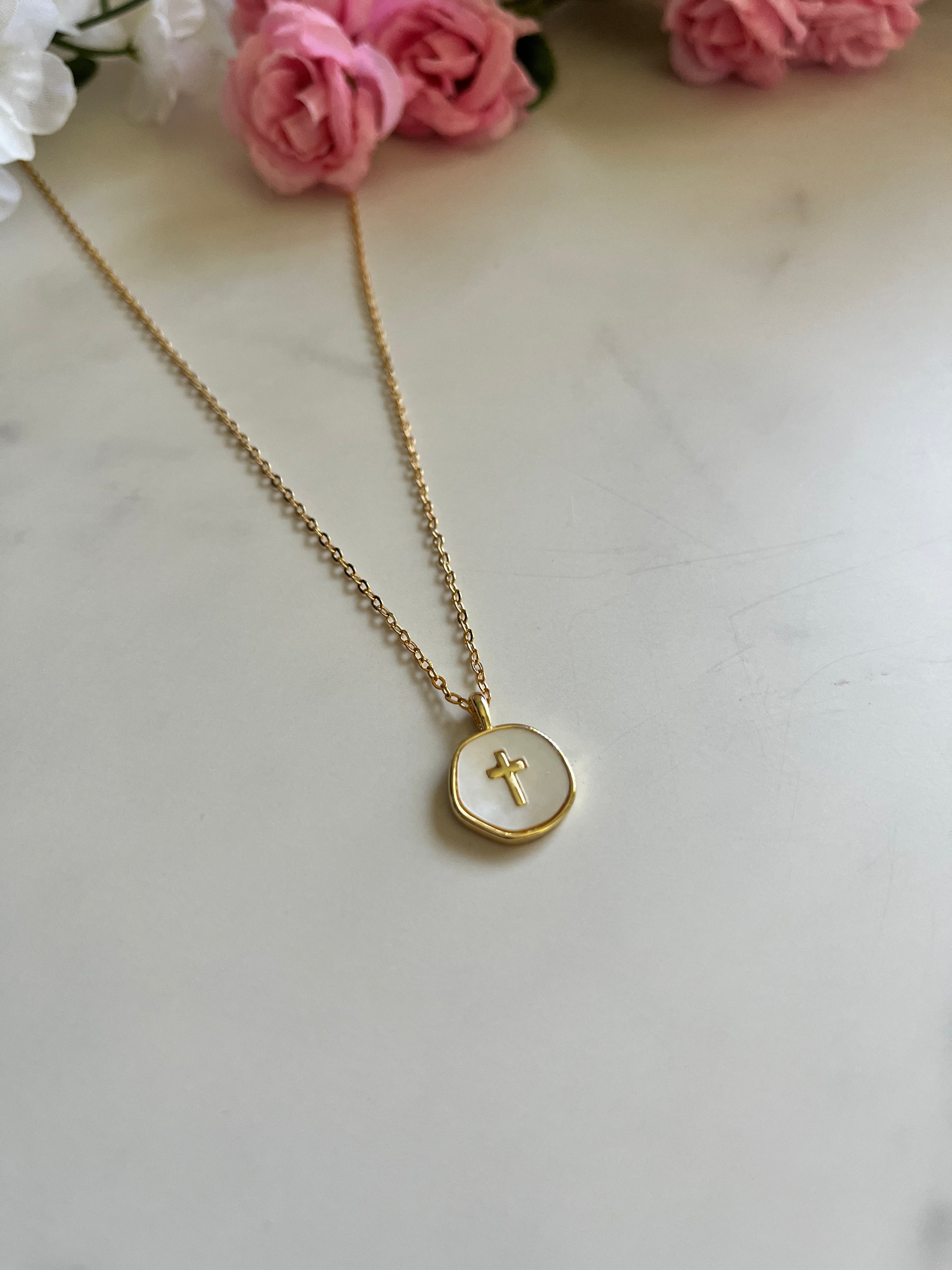 Gold round pendant necklace with cross charm, close view of the thin chain