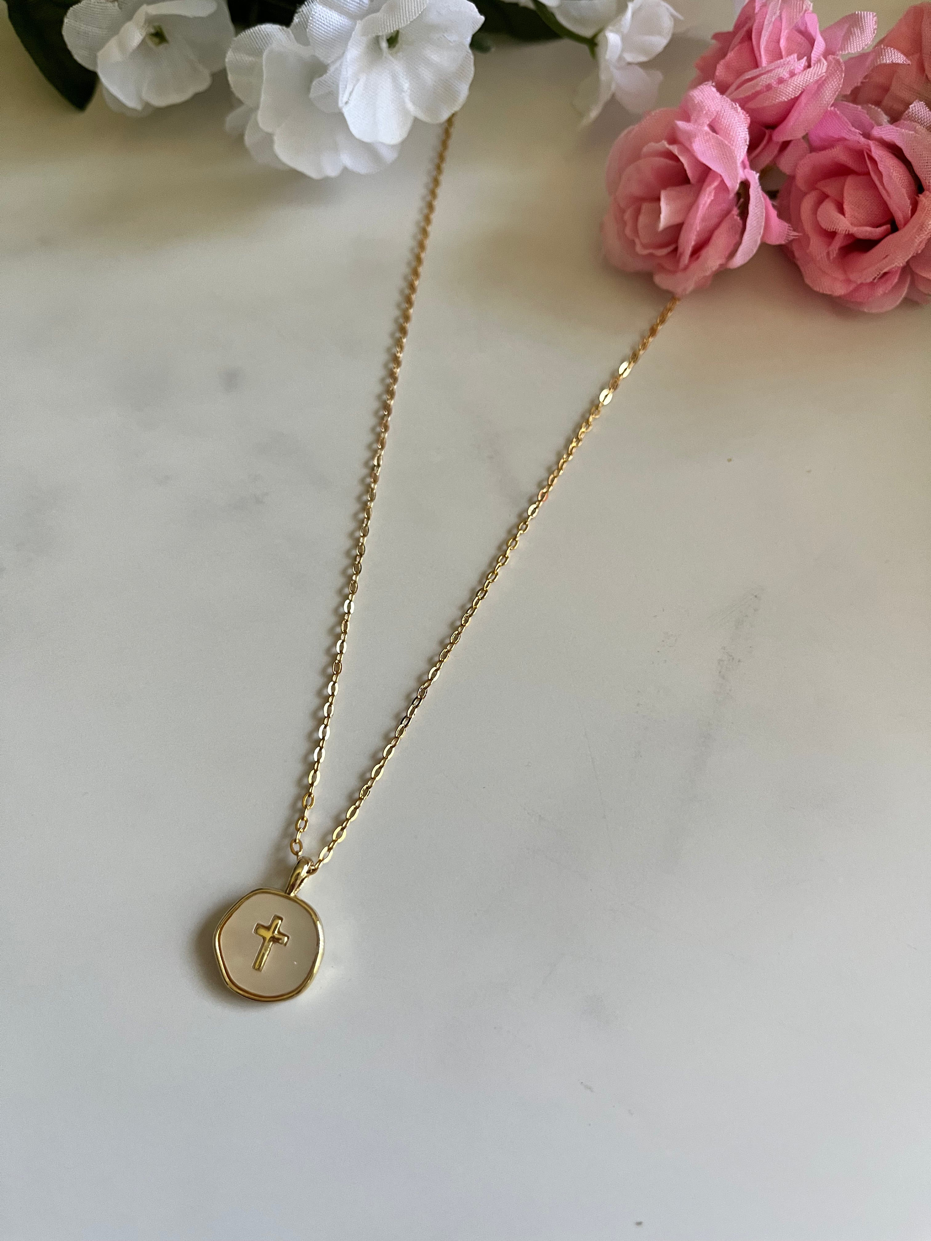 Gold necklace with round pendant cross charm and thin chain, centered view