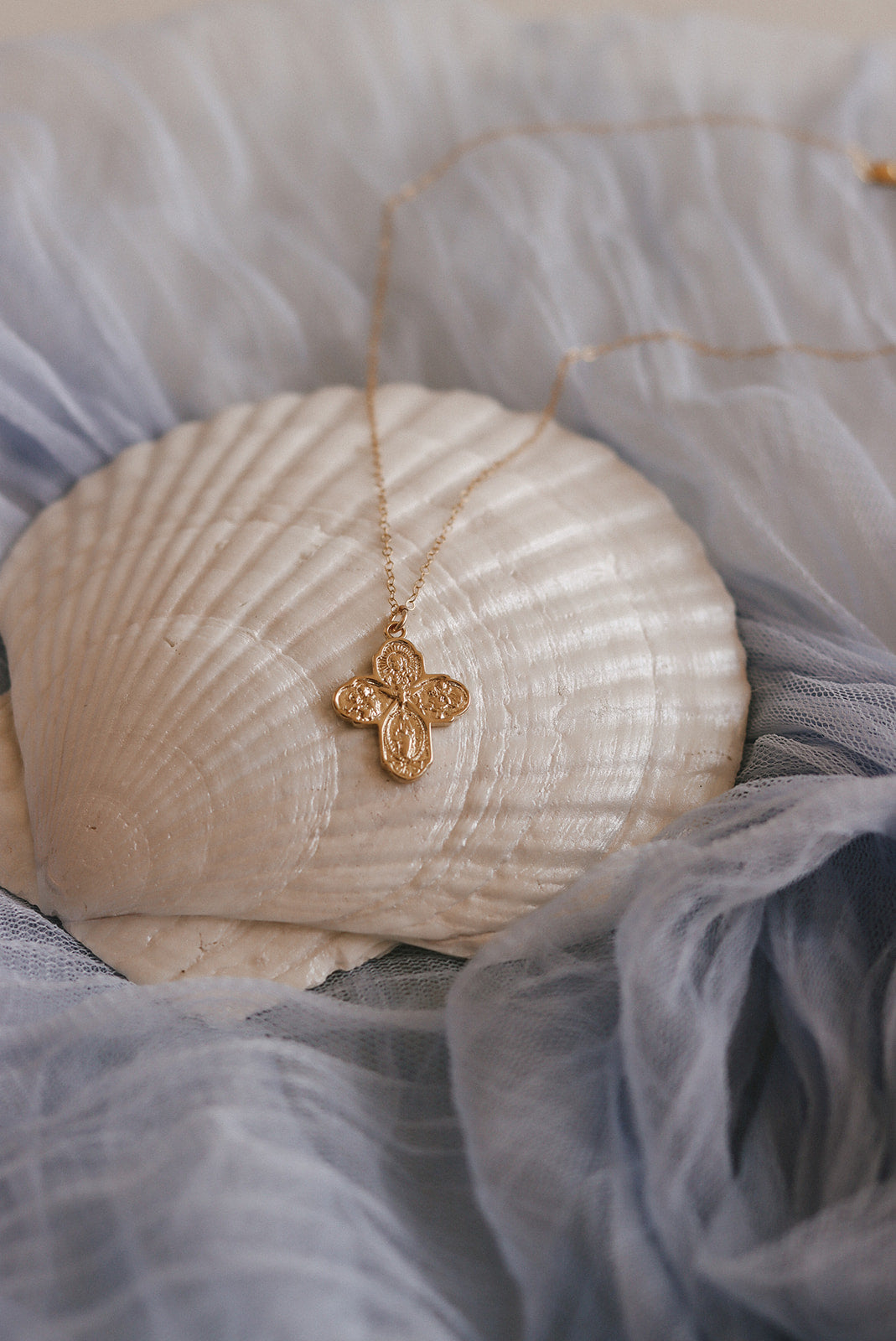 Gold-tone cross pendant necklace with delicate chain, small pendant centered.