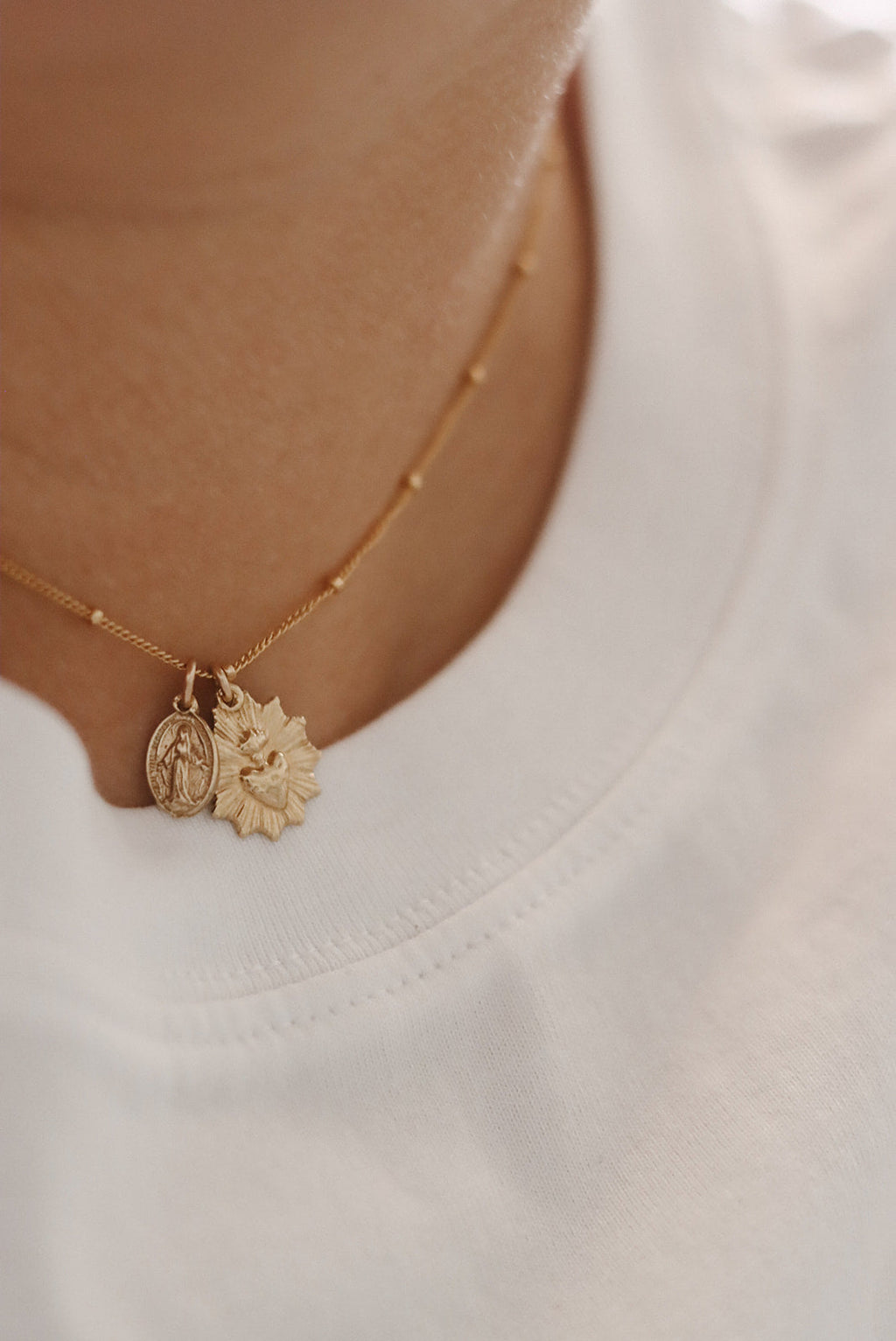 Gold-tone heart and medal pendant necklace with chain and charm near neckline