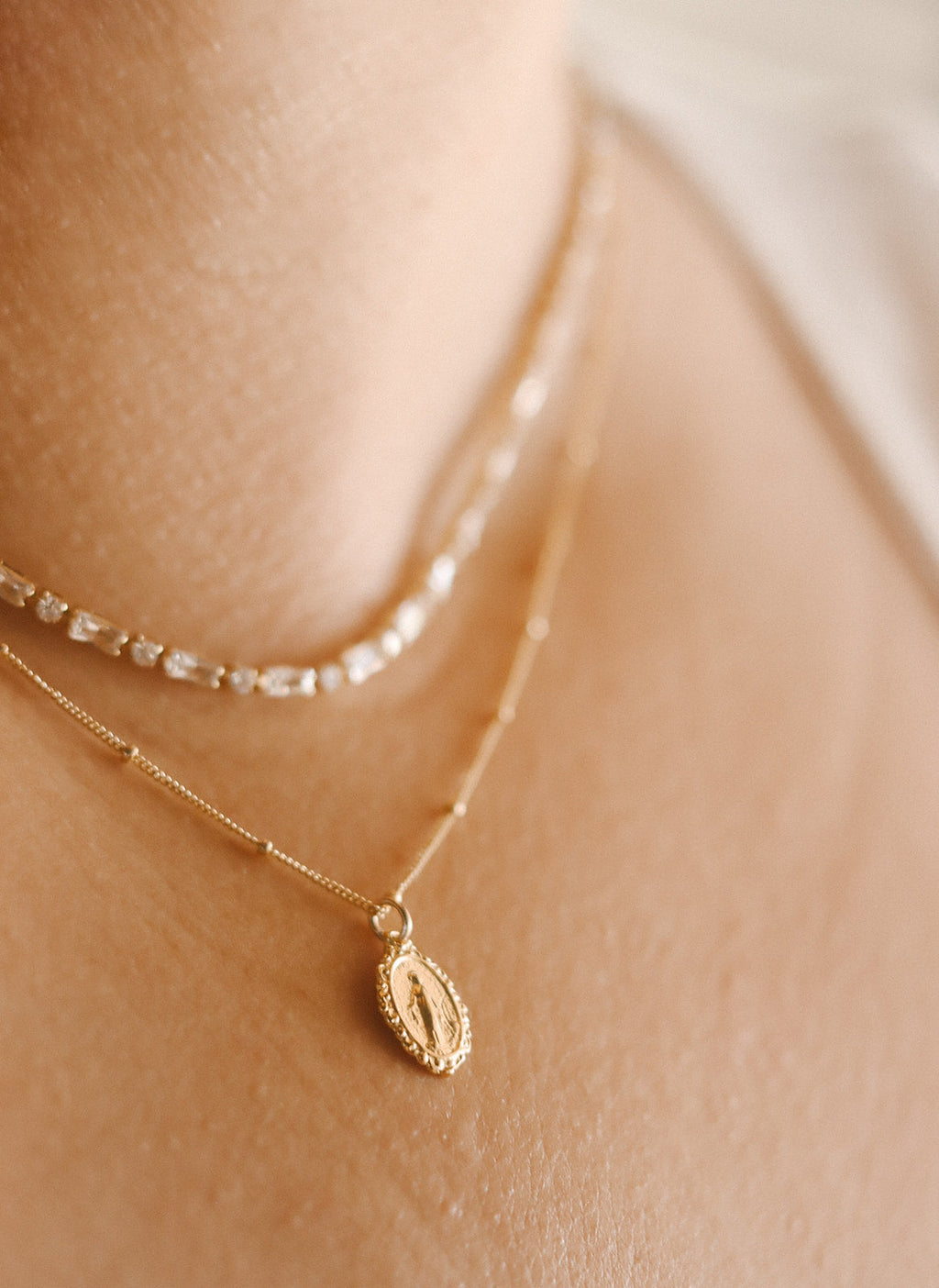 Gold-tone necklace with oval medal charm and sparkling bead chain section