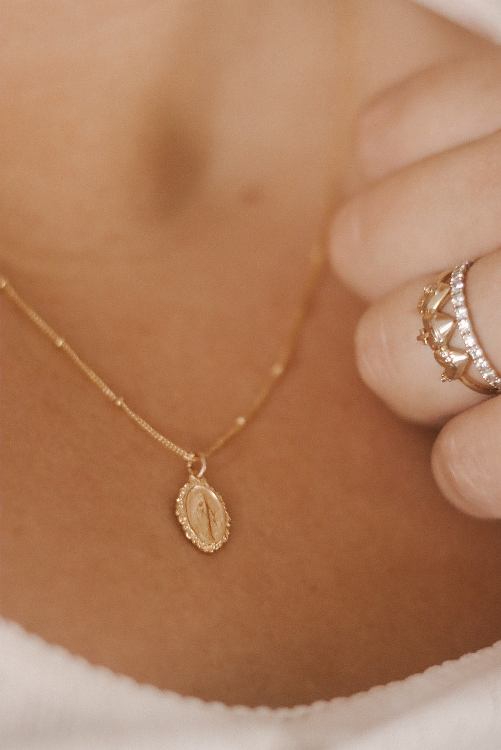 Close-up of gold-tone oval medal charm necklace with delicate chain