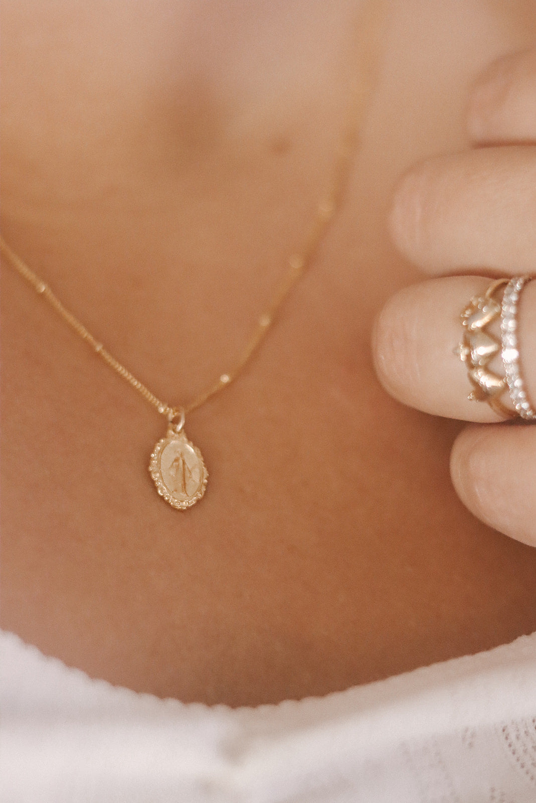 Gold-tone pendant necklace with small oval medal and short chain close-up