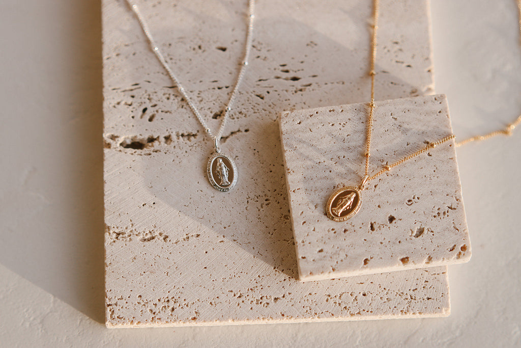 Two necklaces on speckled card: silver and gold oval pendants on thin chains
