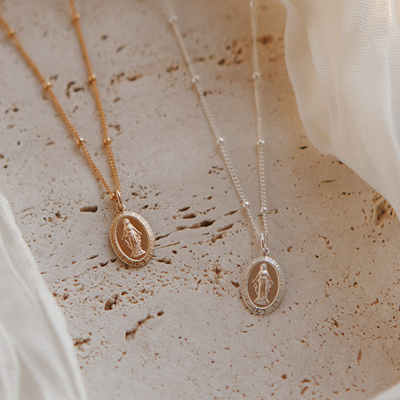Two necklaces on speckled card: gold and silver oval pendants on delicate chains