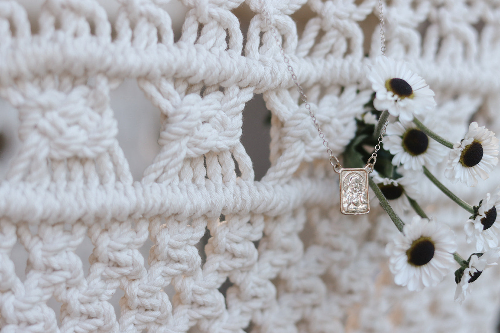 Silver scapular necklace with rectangular saint medal pendant over white crochet
