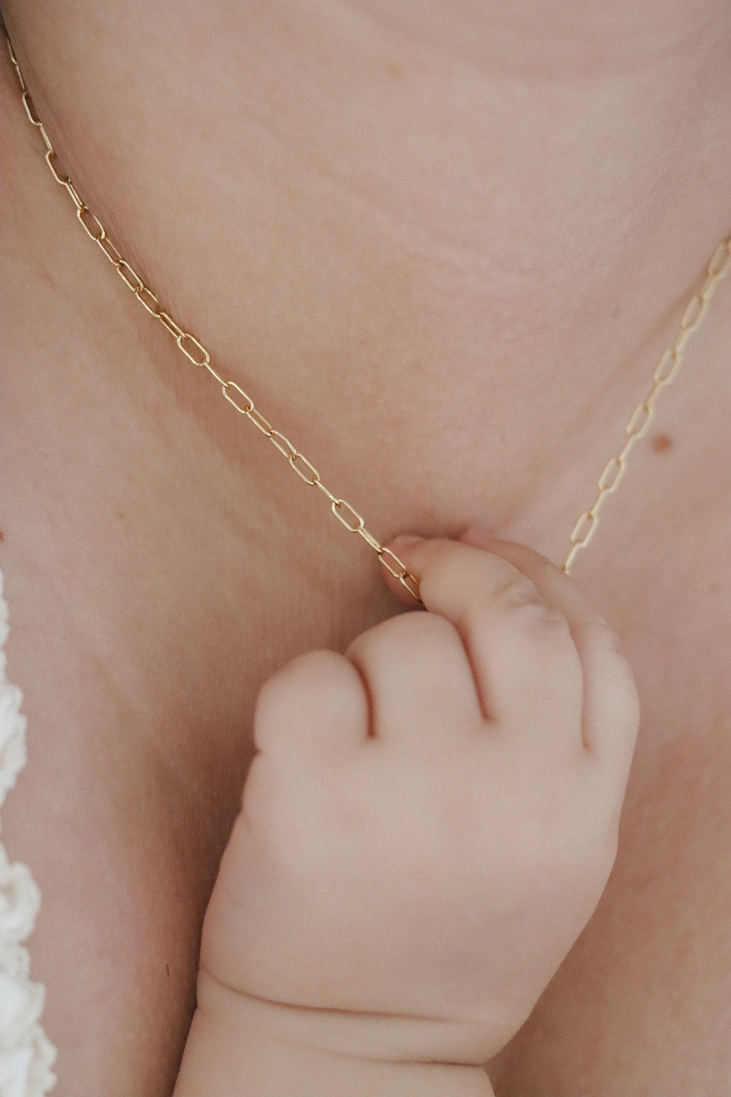 Scapular charm necklace with gold-tone chain resting on a hand