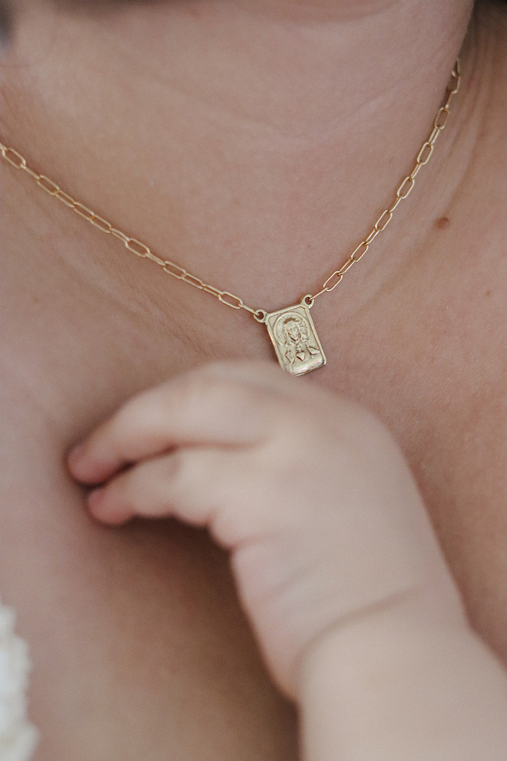 Gold paperclip scapular necklace with small square pendant on neck