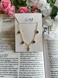 Gold charm necklace with red heart stones and a gold cross pendant