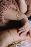 Gold-tone bracelet with oval medal charm on child's wrist, close-up