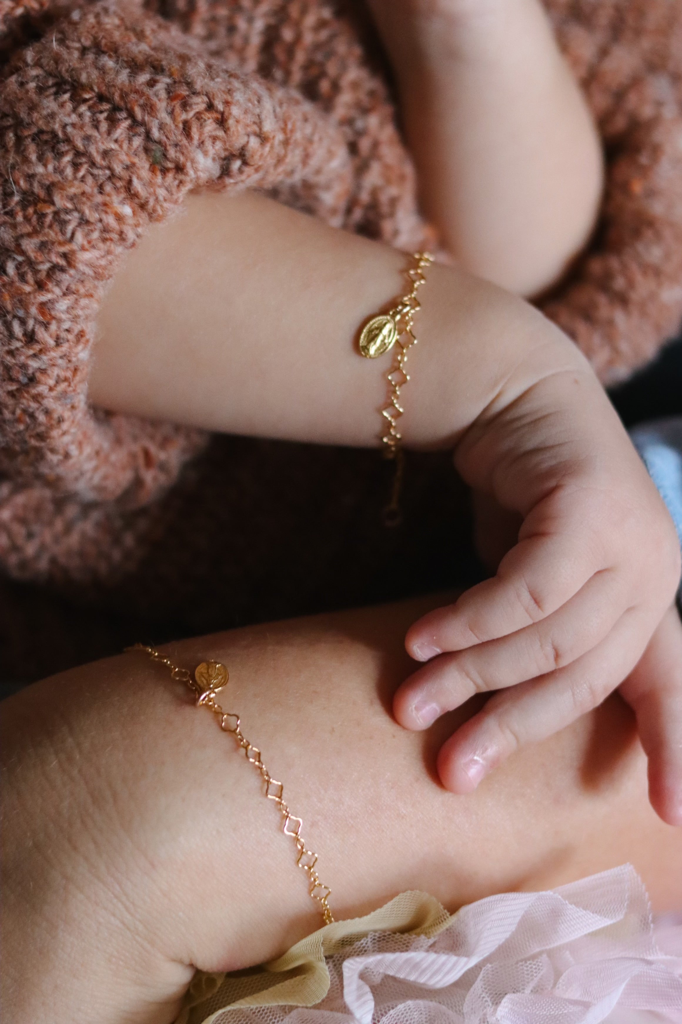 Gold-tone bracelet with oval medal charm on child's wrist, close-up