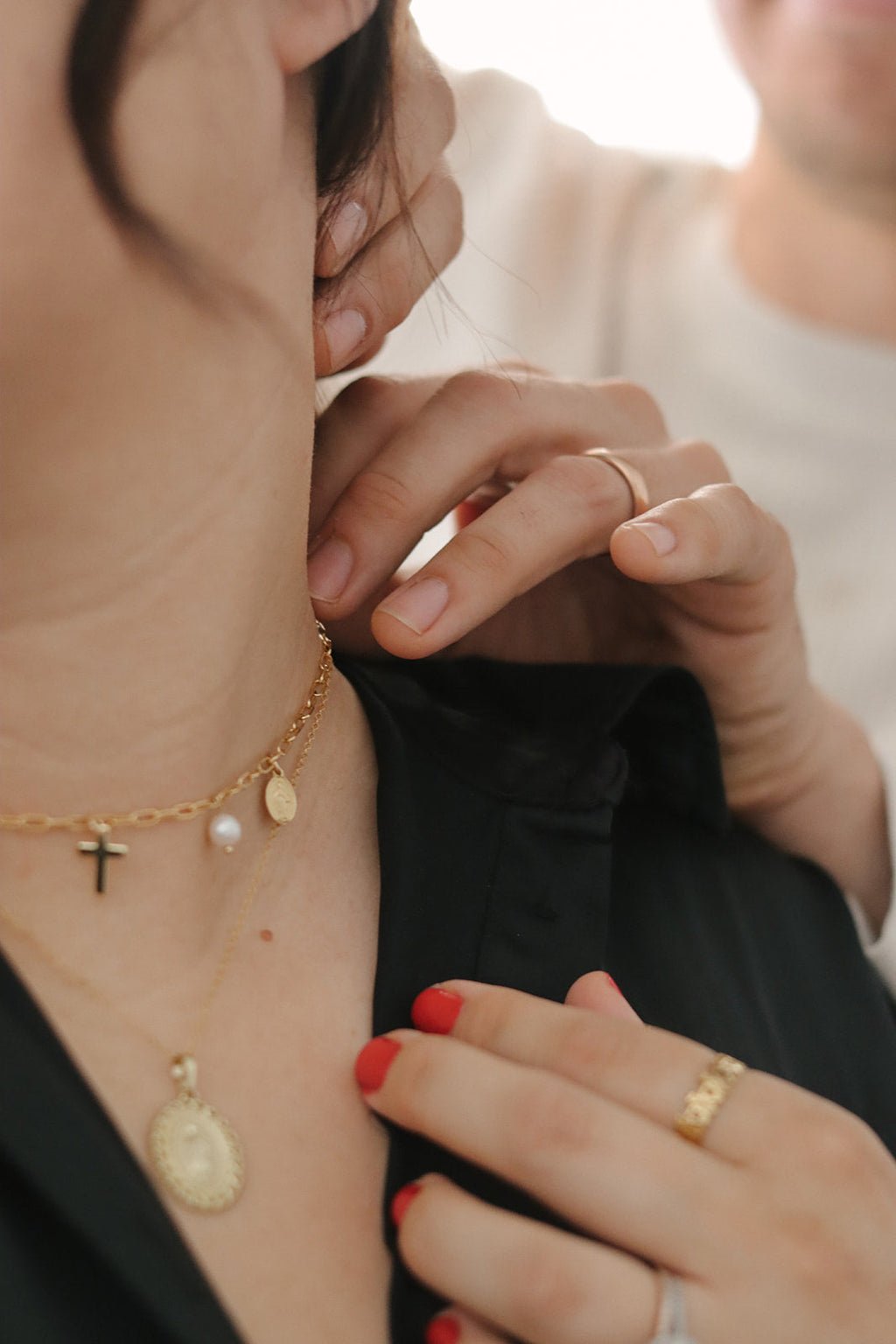 Gold cross and pearl necklace worn at neckline with charm pendants