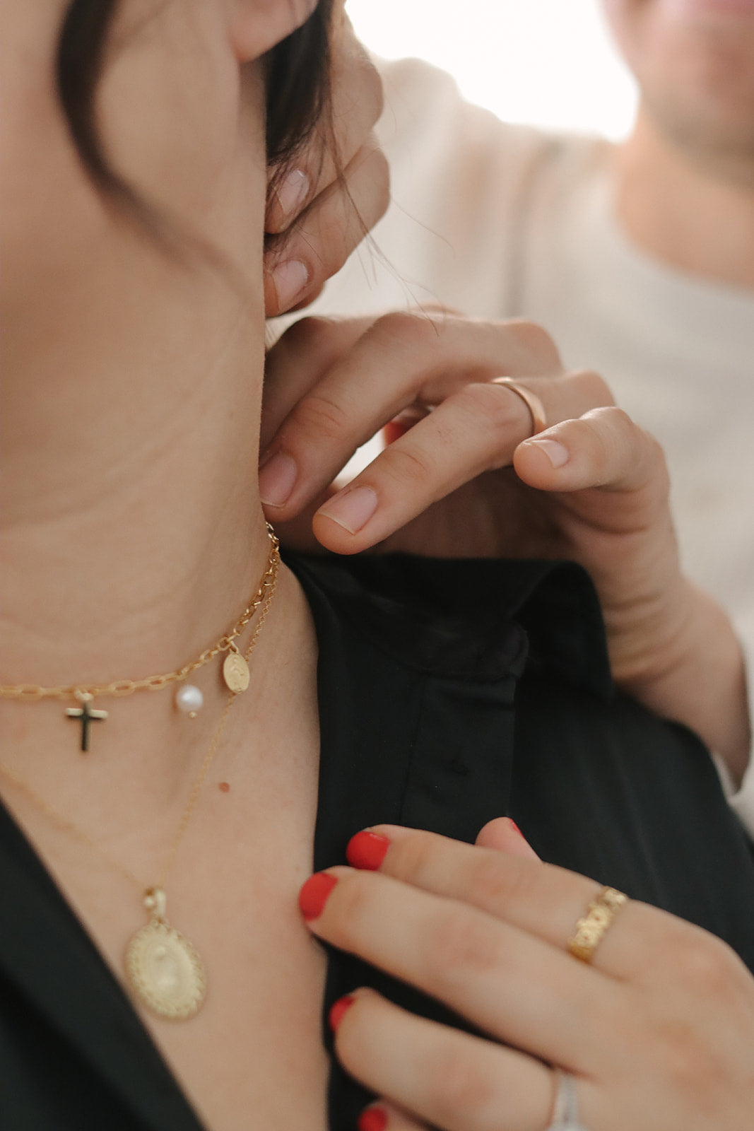 Gold cross and pearl necklace worn at neckline with charm pendants