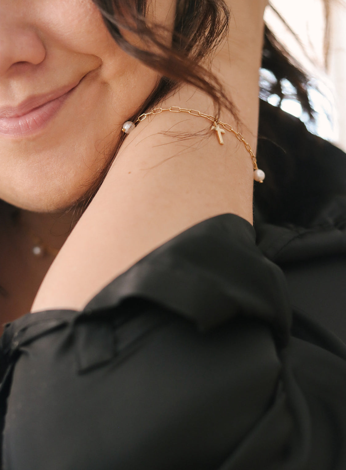 Gold link bracelet with cross charm and white pearl bead on wrist