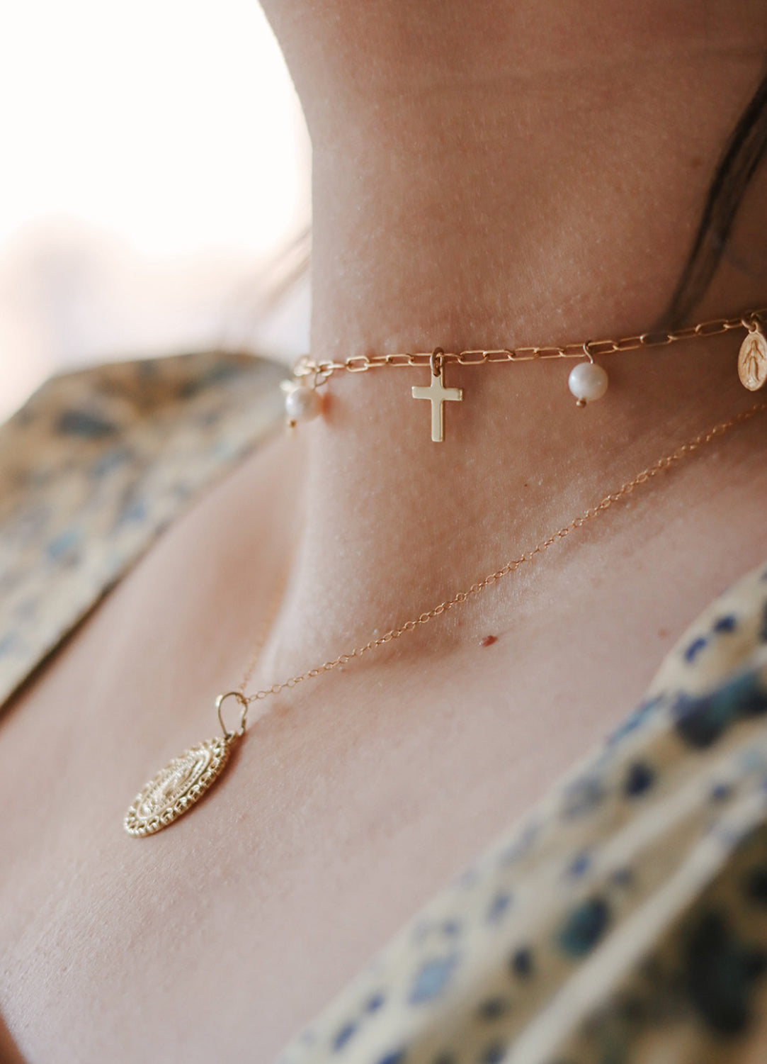 Gold-tone necklace with cross charm and small pearl beads along the chain.