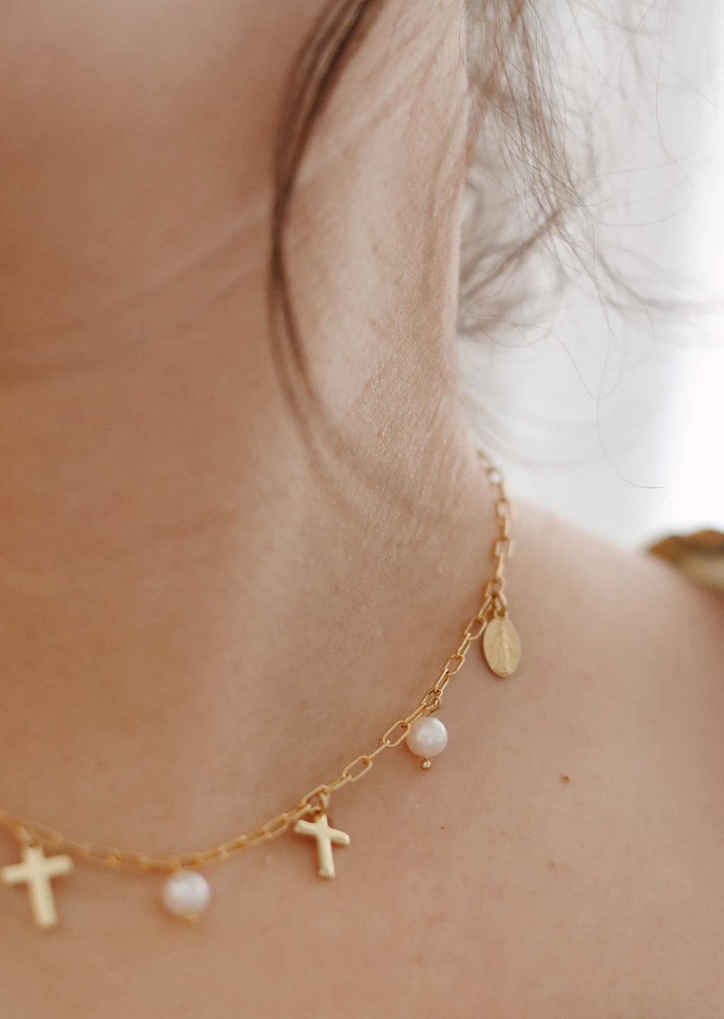Gold-tone necklace with cross charms and small pearl beads on a delicate chain.