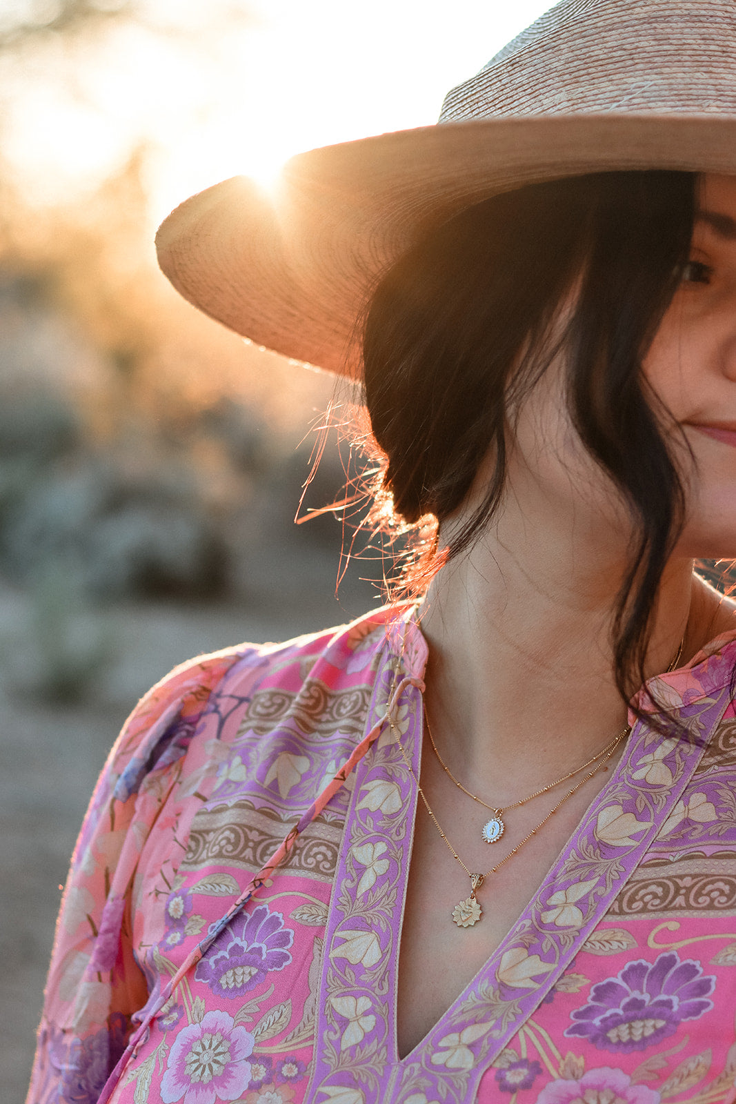 Gold-tone scalloped heart charm necklace on a woman in a purple patterned top