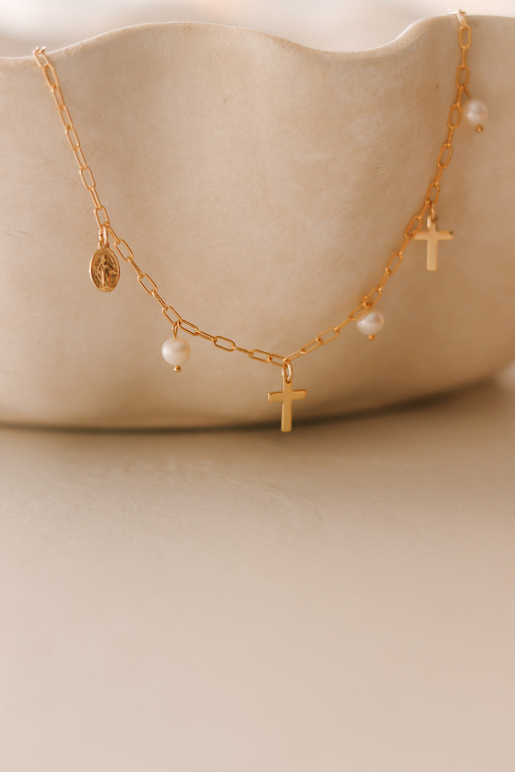 Gold cross pendant necklace with pearl bead details and charm accents